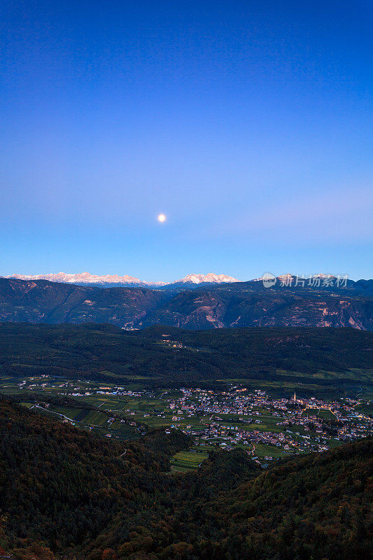 月亮升起在Dolomites与Caldaro / Kaltern村